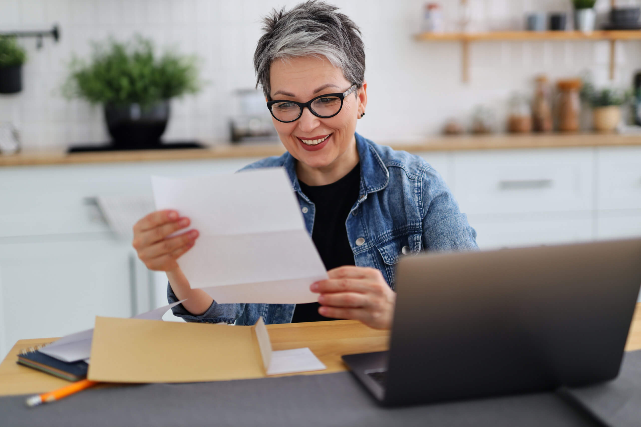 woman smiling as she reads a piece of paper.